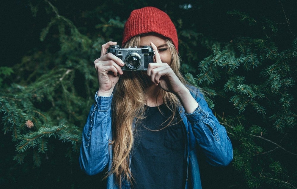 A young woman in a red hat taking a photograph