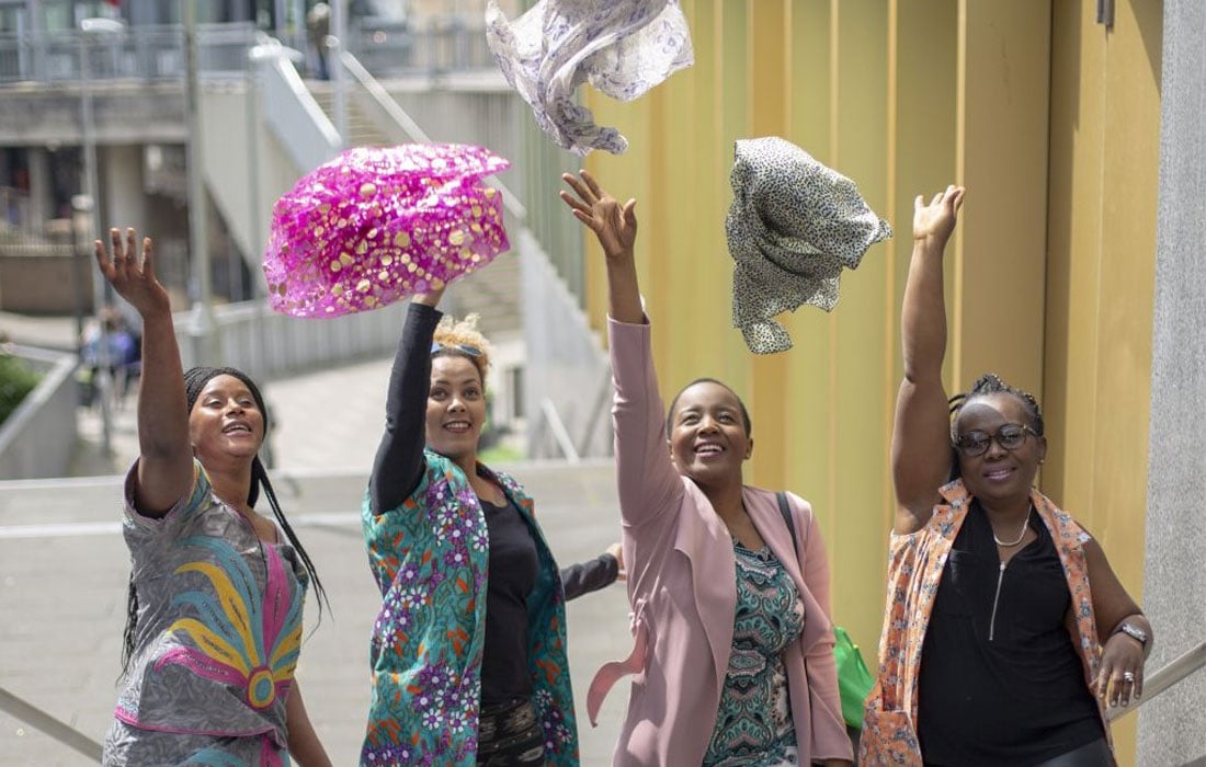 Photo of four women throwing scarfs into the air