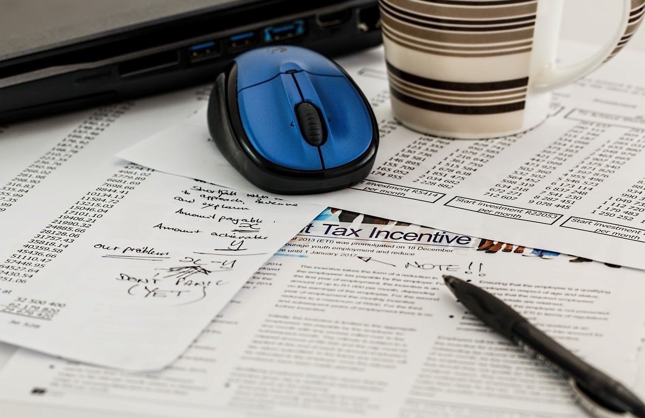 A photo of forms, a  pen, a computer mouse and a mug