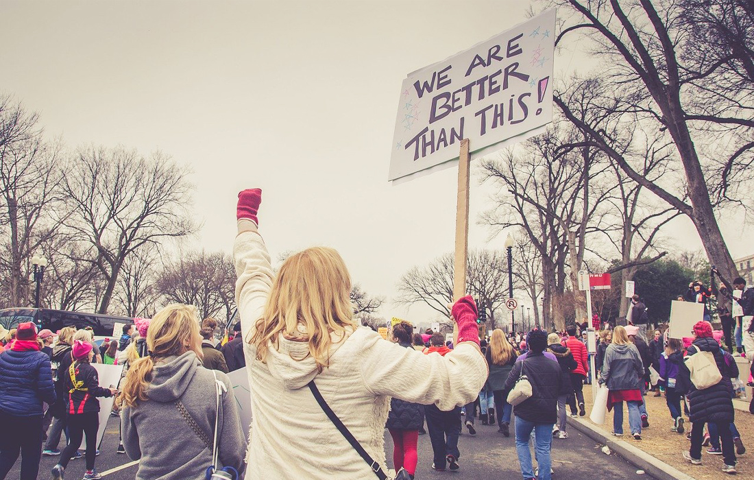 A woman protesting carry a sign that says 'we deserve better'