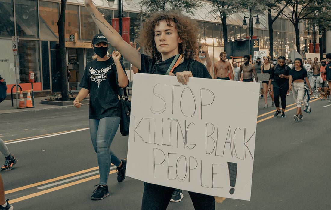 woman marching with banner 'stop killing black people'