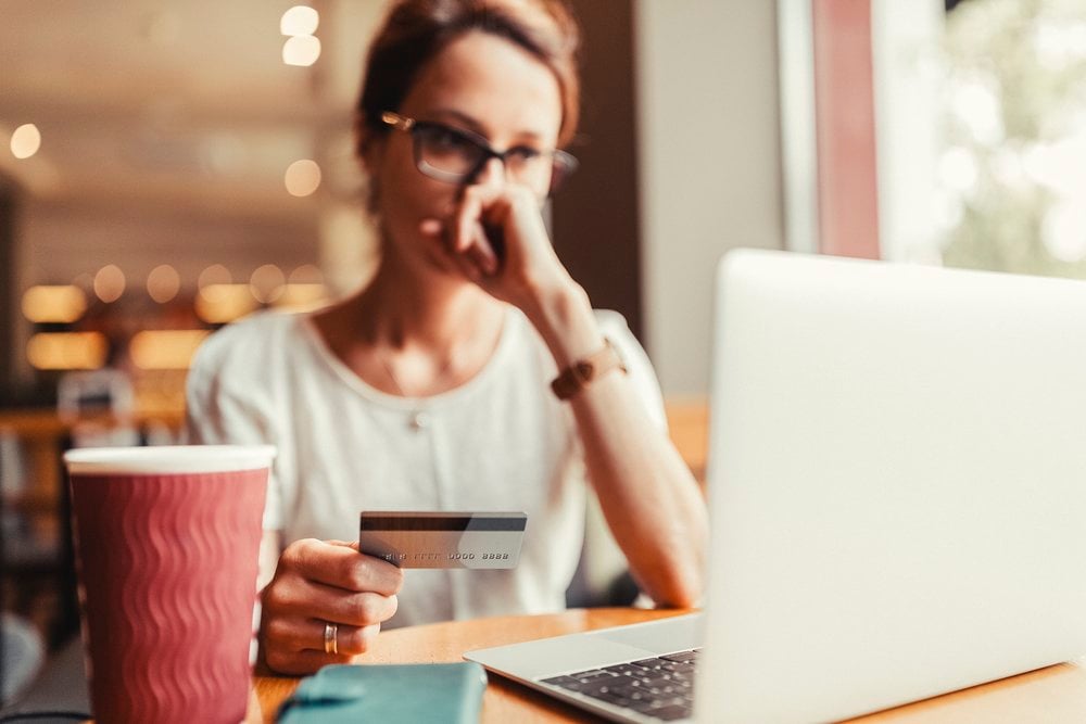 Woman debating online purchase with credit card