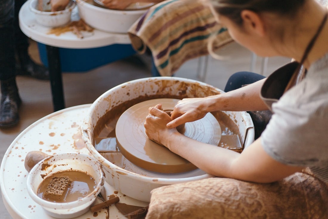 Someone working with clay. Photographed over their left shoulder