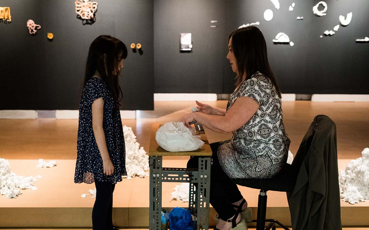 a girl watches a pottery demonstration