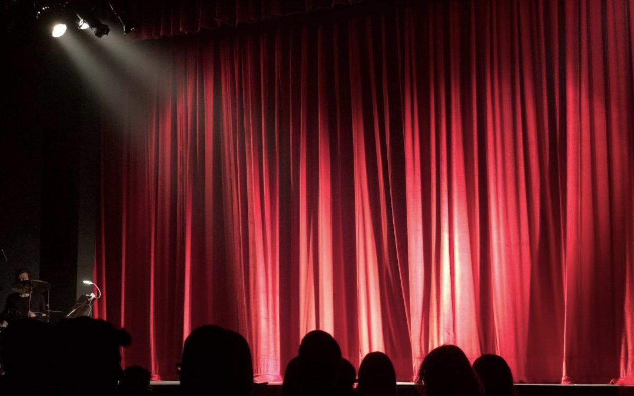 crowd waits infront of an empty theatre stage