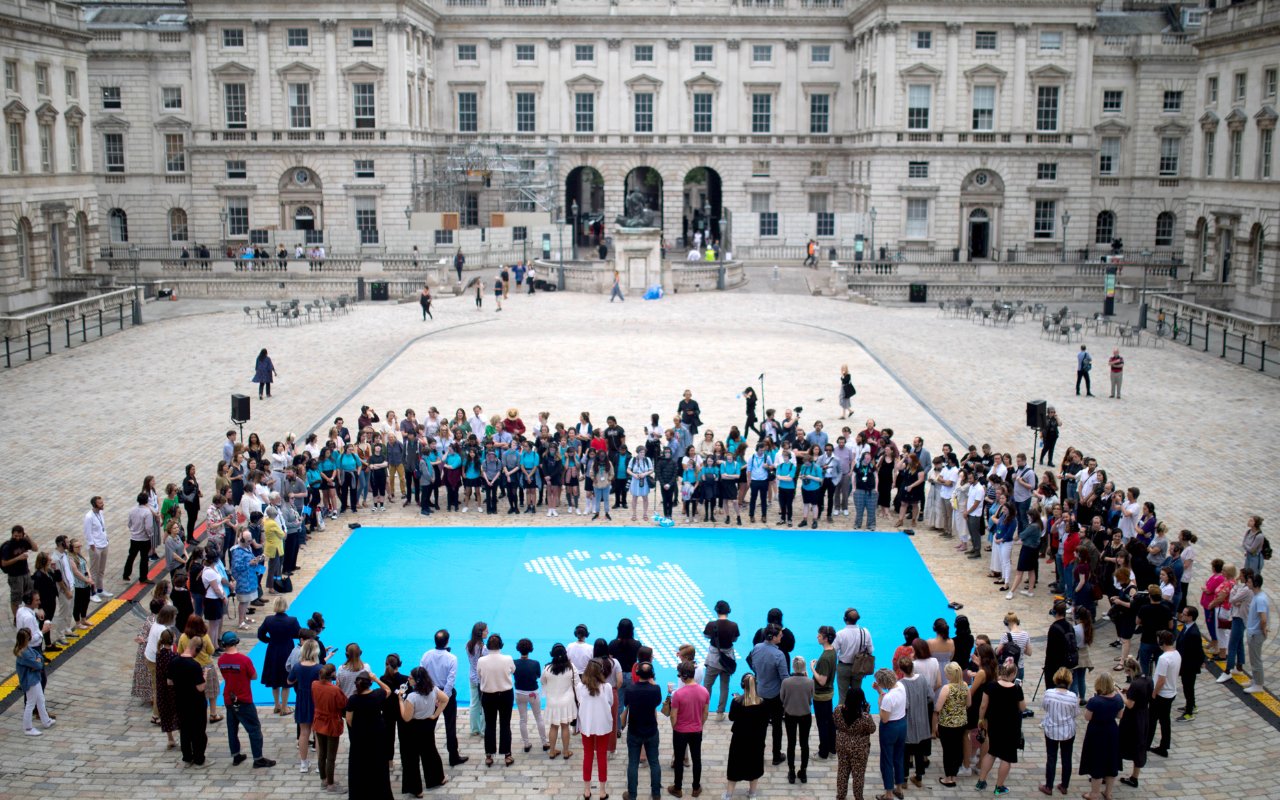 A group of people look over a flag in a courtyard