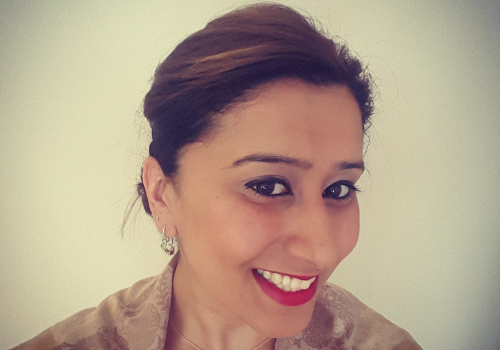 Joshna Rughani, Artfinder CEO. She has dark hair, is wearing silver earrings, red lipstick and dark eyeliner. She is smiling at the camera.