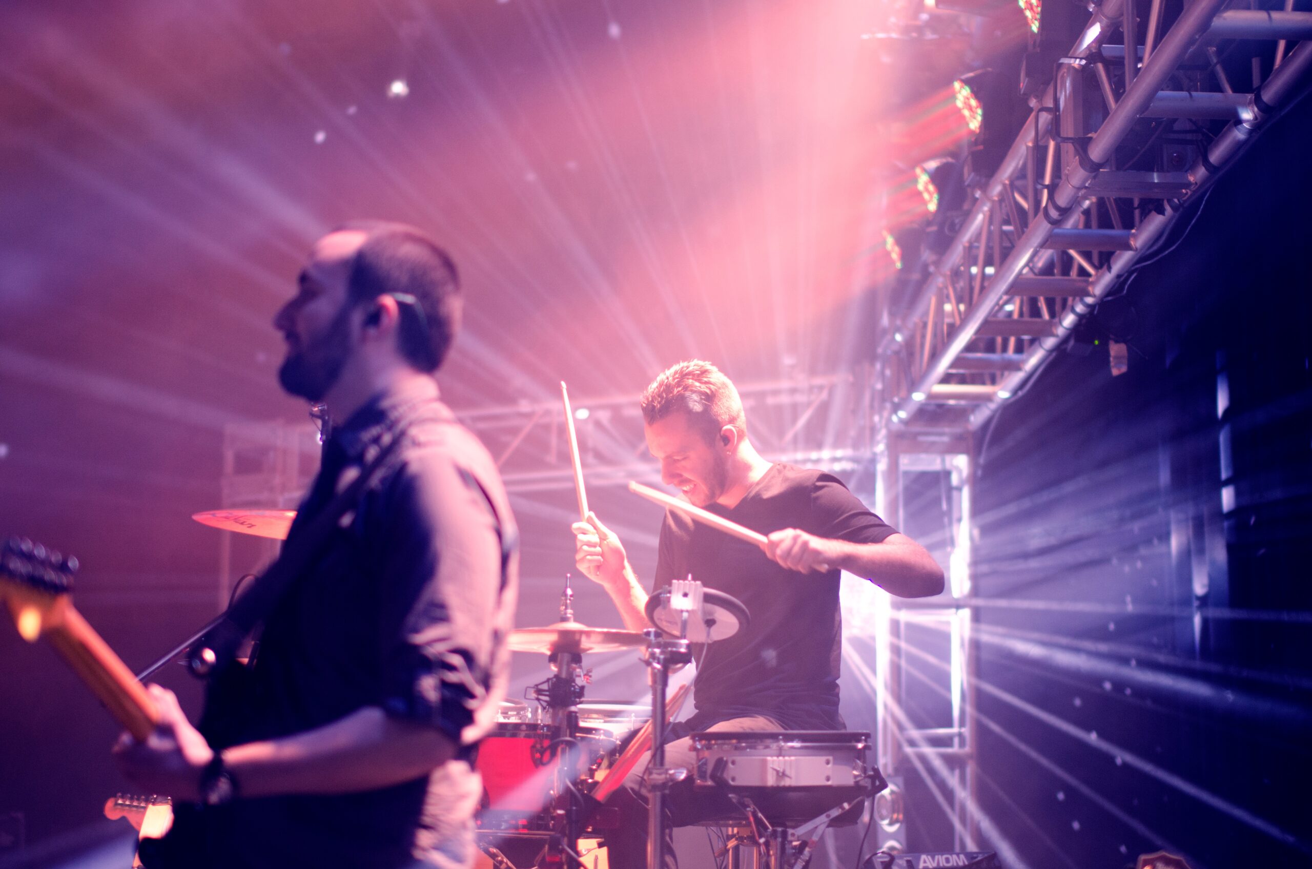 A guitarist and drummer play music on stage