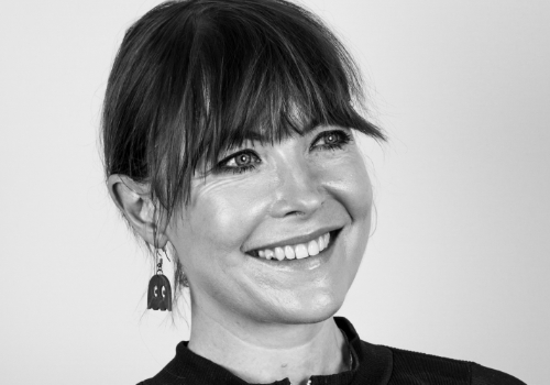 Dr Jo Twist OBE, Chief Executive Officer BPI. A black & white image. Twist is a white woman, she is smiling looking upwards, and has a full fringe with hair tied up.