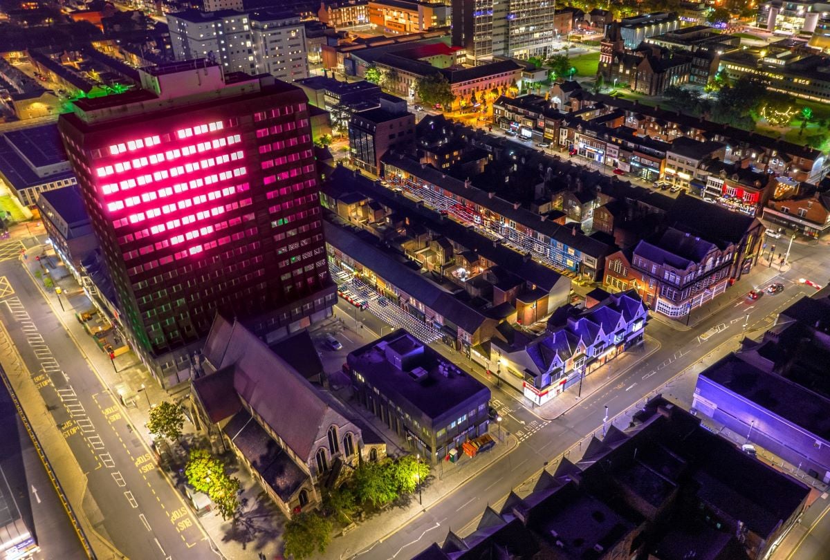 Stuart Langley’s public art work ‘beating heart’, commissioned by Middlesbrough Council. A Birdseye image of Middlesborough, showing a large block of flats with a large projection of a heart. It is surrounded by houses, other buildings and roads.