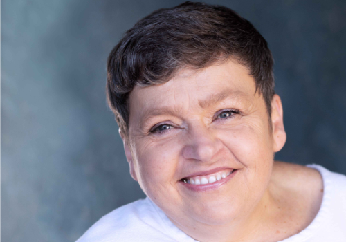 Headshot of Sarah Beer, Ramps Cymru, Director for Change. She is a middle-aged woman with short brown hair. She wears a white t-shirt, and is smiling at the camera.