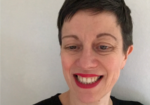 Anna Williams, Chief Operating Officer, Birmingham Royal Ballet. She is a white women with short brown hair. She is looking down and smiling. She wears red lipstick.