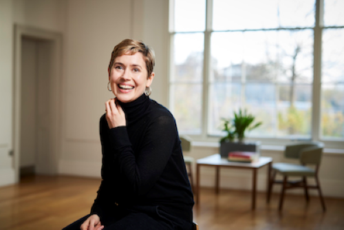 Sarah Philp, Deputy Director, Delfina Foundation. She is a white woman with short, blonde hair wearing a black, turtleneck jumper. She sits in a large room.