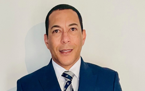 Professor Randall Whittaker, Principal and CEO, Rose Bruford College. He is a man with short, dark hair wearing a dark blue suit, white shirt, and grey and blue tie. He is photographed against a white wall.