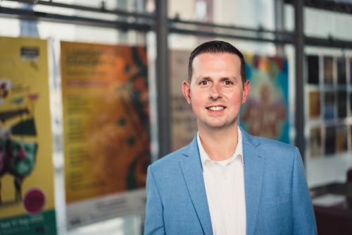 Christopher Glasgow, incoming Chief Executive, Perth Theatre and Concert Hall. He is a man with brown hair and eyes, wearing a blue blazer and white shirt. He smiles at the camera.