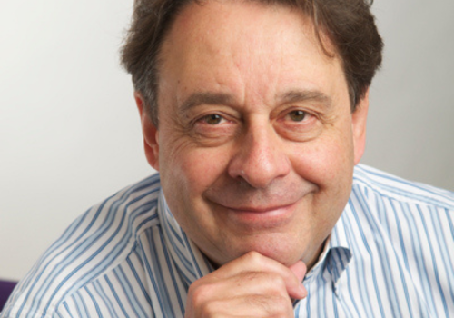 Graham Sheffield, Chair at Birmingham's BOA Group. He is photographed sat down wearing a blue/white striped shirt, resting his hand on his chin. He smiles at the camera.