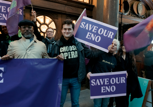 Protesters outside The Coliseum hold purple placards reading 'Save our ENO'