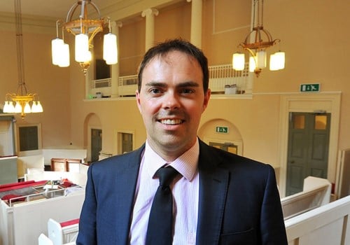 Steve Miller, a man with short black hair wearing a blue suit and tie