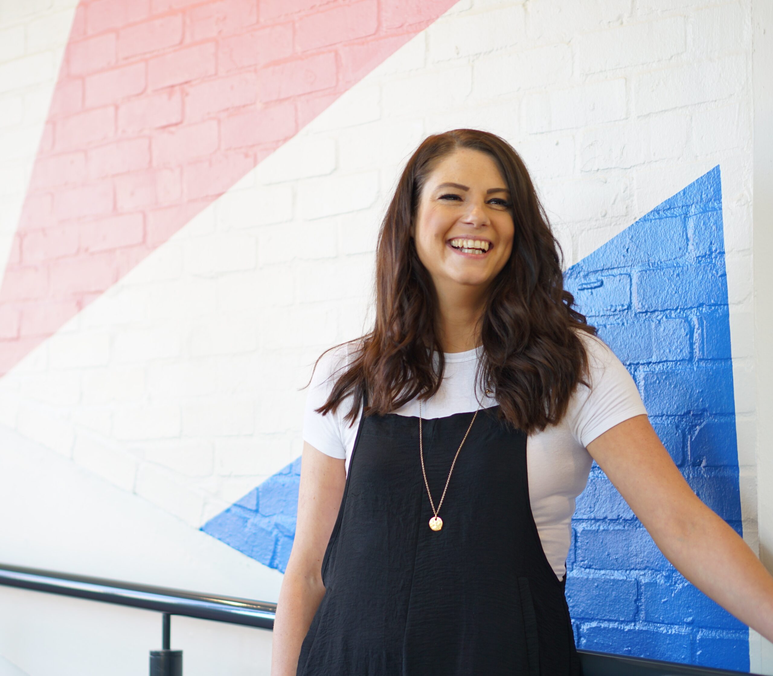 Natasha Rickman stands in front of a painted brick wall