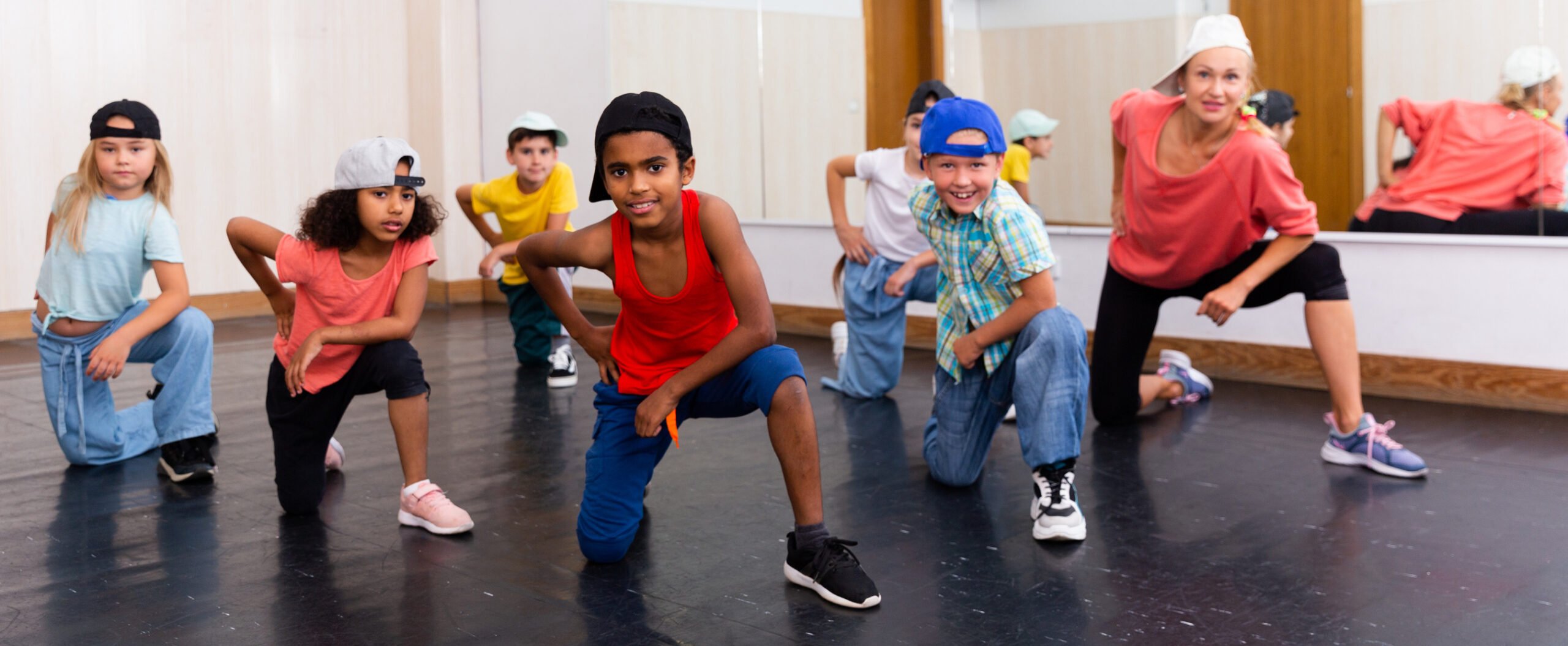 Group of happy tweens with female teacher practicing hip hop in modern dance studio